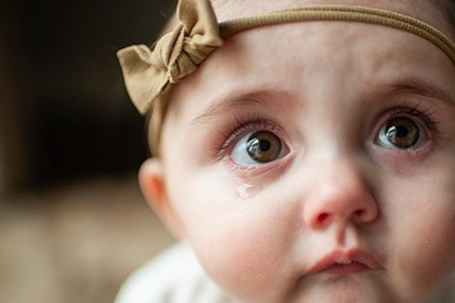 A brown-eyed infant with a downturned mouth and a sad look.