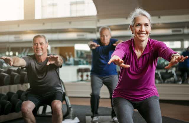 Trois adultes aux cheveux grisonnants faisant de l'exercice dans un gymnase