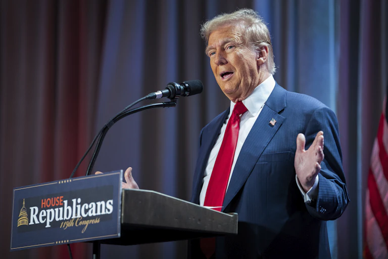 A man in a navy suit and tie gestures while speaking into a microphone on a podium that says 'House Republicans 19th Congress'