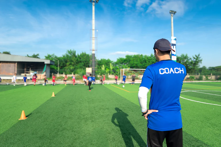 A sports coach looks on as his team trains