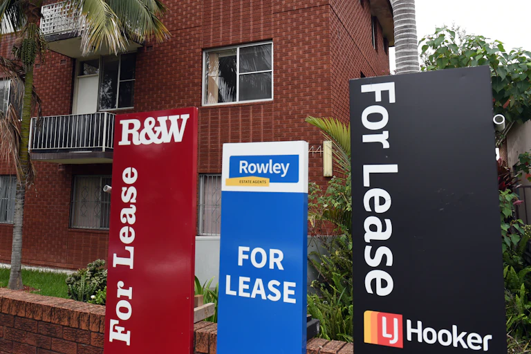 Three lease signs in front of a brick apartment building
