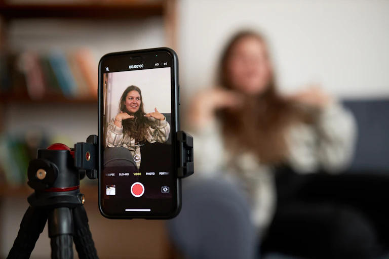 Close up of a phone on a tripod filming a woman sitting on a couch