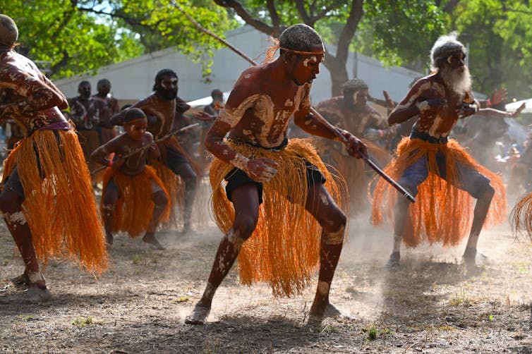 A group of Aboriginal men in traditional dress perform a dance