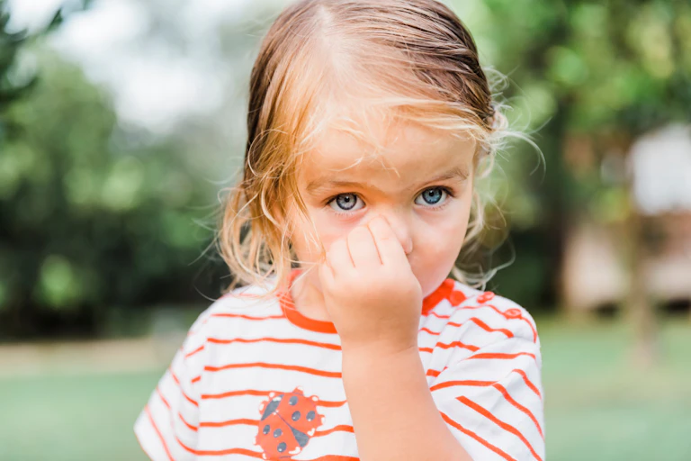 Toddler picking nose in garden