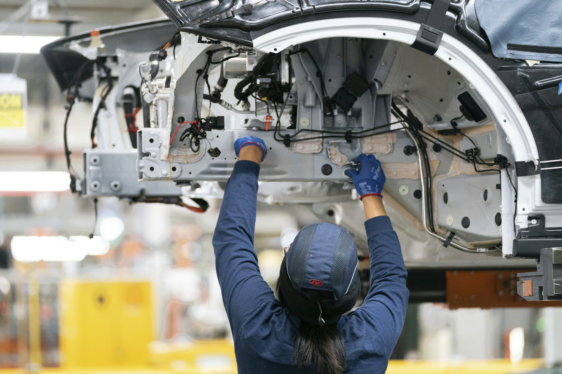 An employee works on a car on an assembly line