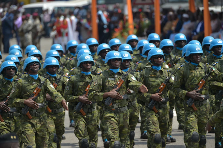Soldiers wearing UN blue helmets and carrying AK 47s march.