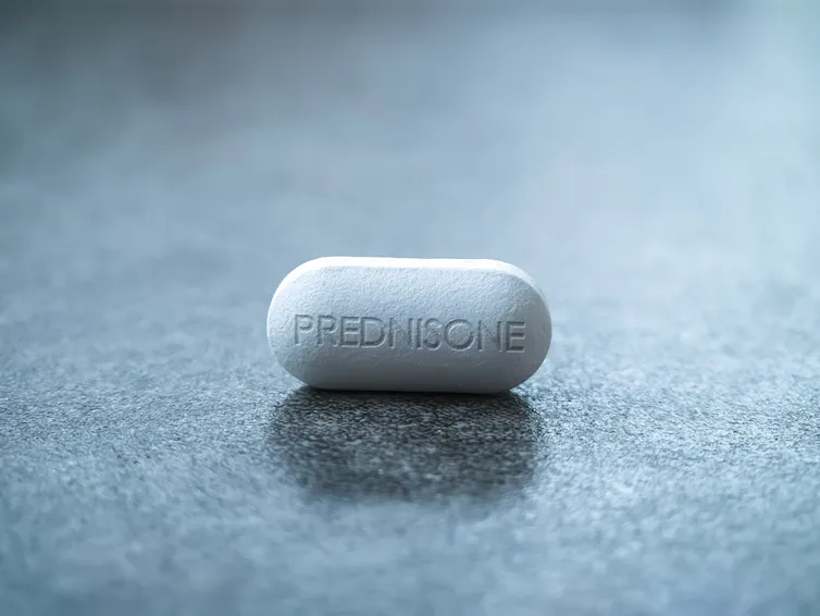 A prednisone pill on grey background.
