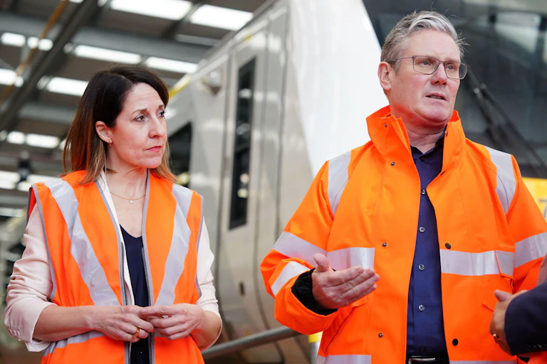 Liz Kendall and Keir Starmer in orange high vis jackets, standing in front of a train