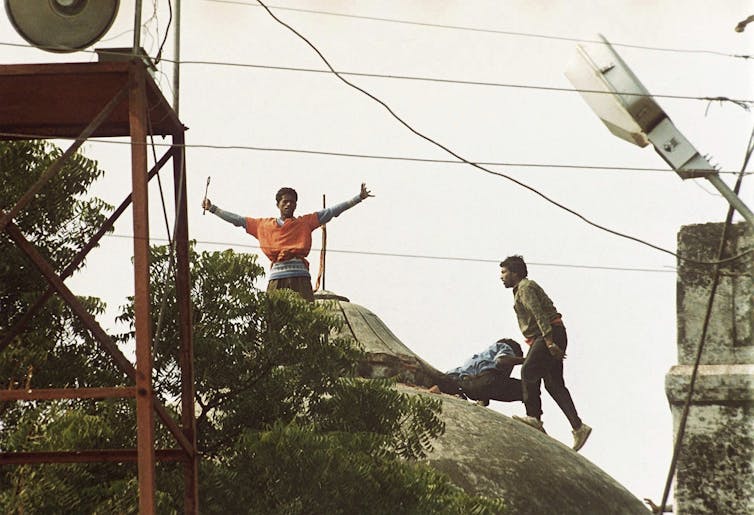 Men celebrate on top of the toppled dome of a mosque.