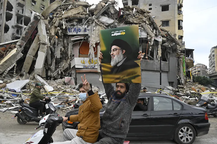 A man on the back of a motorbike carries a picture of Hassan Nasrallah.