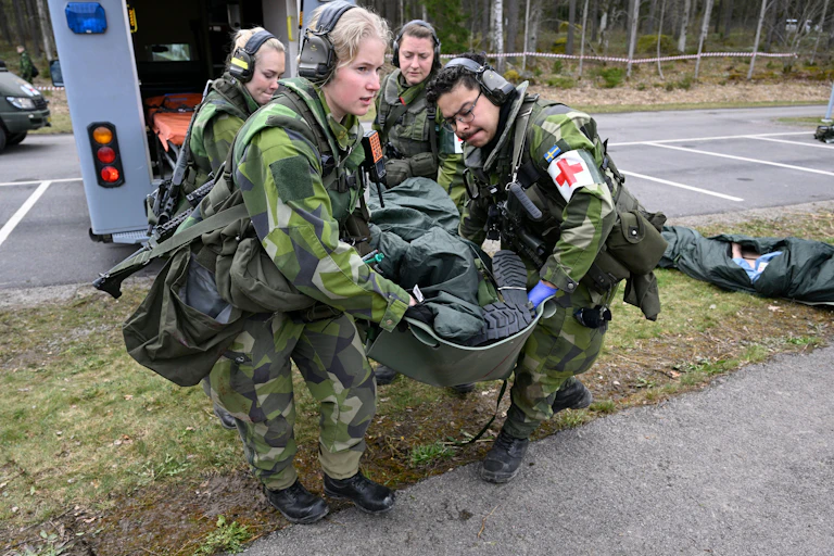 Two women and two men with a stretcher as part of a civil defense exercise in Sweden.