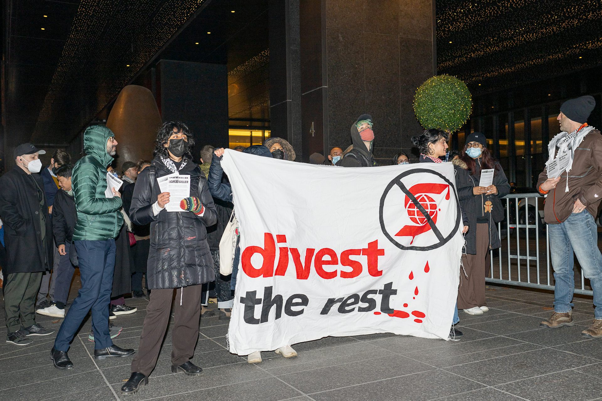 People hold a banner that says divest the rest.
