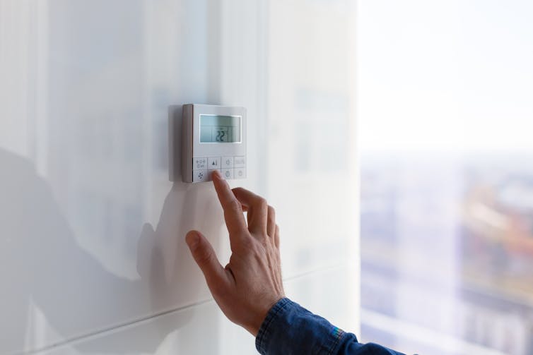The person is adjusting the thermostat.