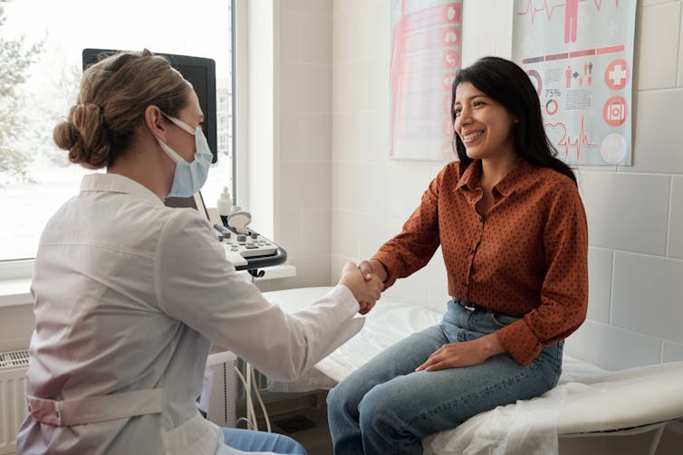 A woman shakes hands with a doctor.