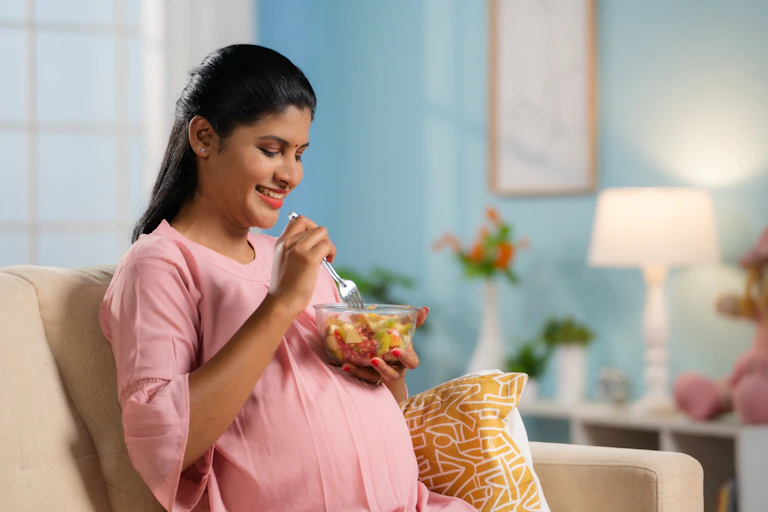 A pregnant woman sitting on a sofa eating