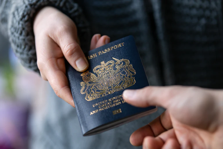 Close up of someone handing a British passport to another person