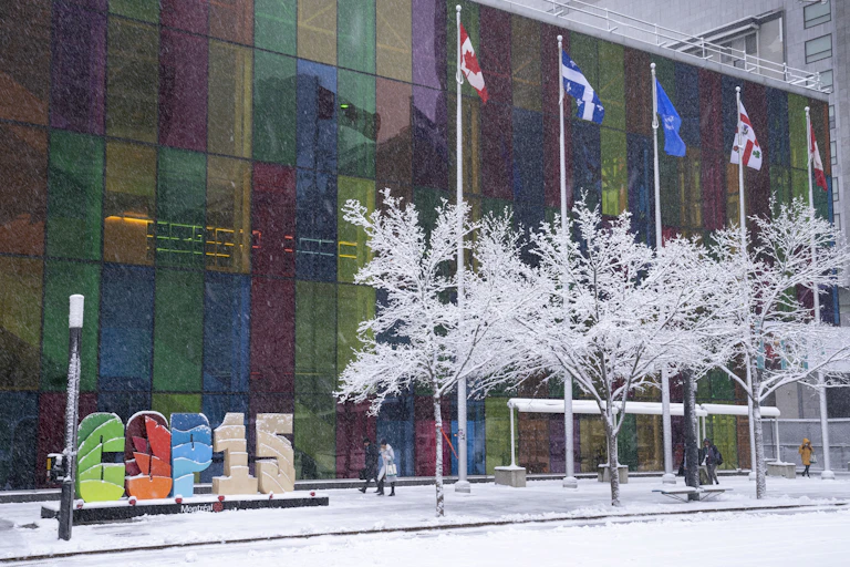 People walk past a building in the snow.