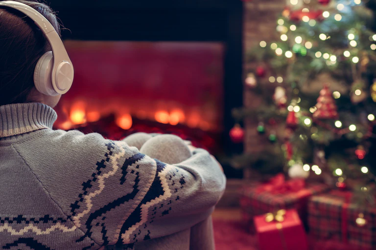 Person wearing headphones looking at a Christmas tree