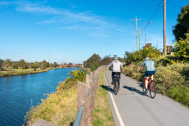 Two cyclists ride along the Maribyrnong River in Melbourne