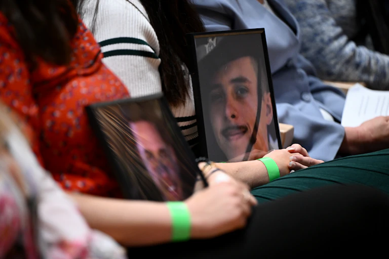 People hold portraits of ADF family and friends who lost their lives to suicide.