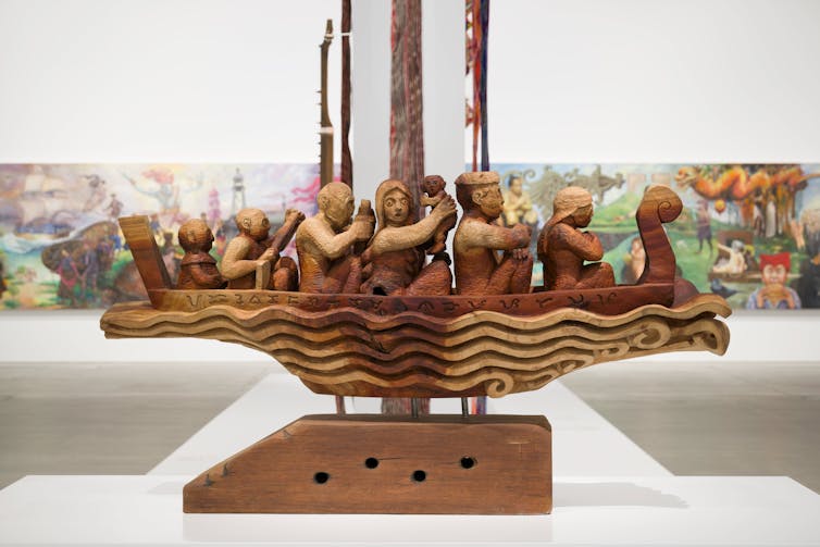 A wooden sculpture of figures in a boat.
