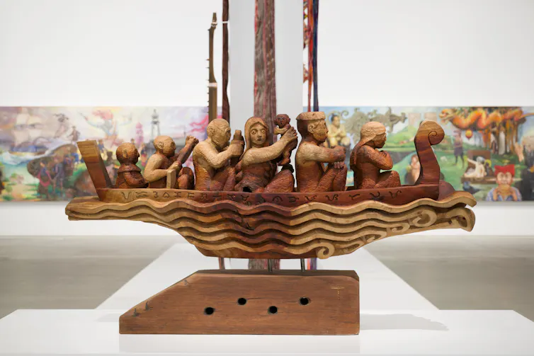 A wooden sculpture of figures in a boat.