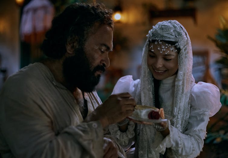 A young woman in white lace and an older, bearded man.