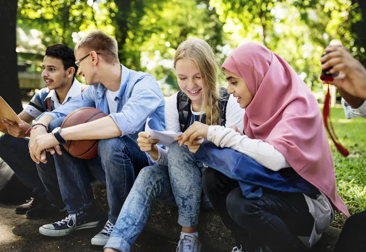 A group of diverse teenagers sitting in a park.