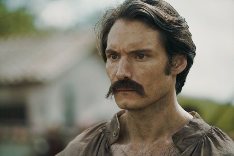 A man with a thick moustache and an intense stare.