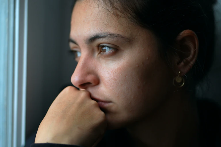 woman rests chin on hand and looks out window
