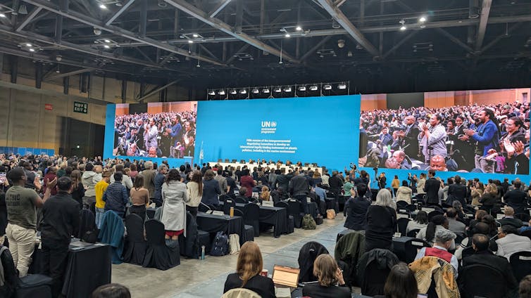 A plenary room filled with people standing up.