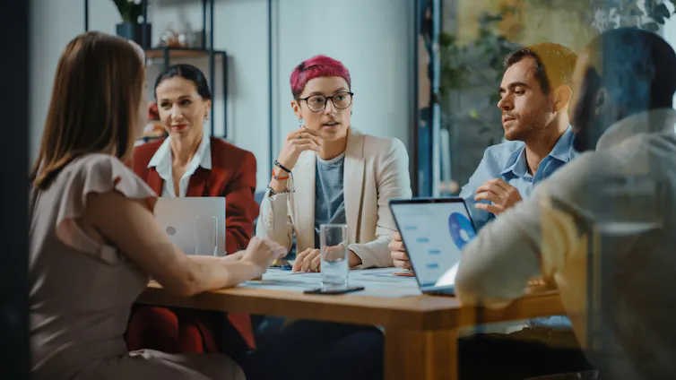 A group of gender-diverse people meet in the workplace.