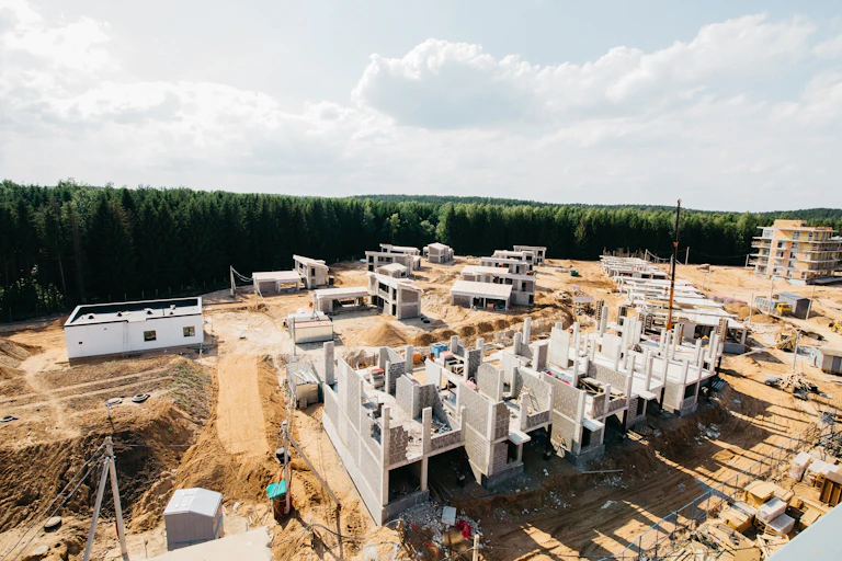 un chantier de construction avec une forêt en fond et un ciel gris