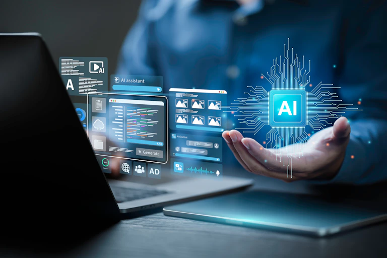 A person, seen from the shoulders down, works on a laptop. One of their hands is raised with the palm facing upwards and an image of a computer chip that says AI in the middle floats above it