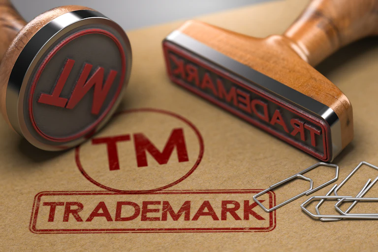 two rubber stamps with the word trademark and the symbol TM over brown paper background