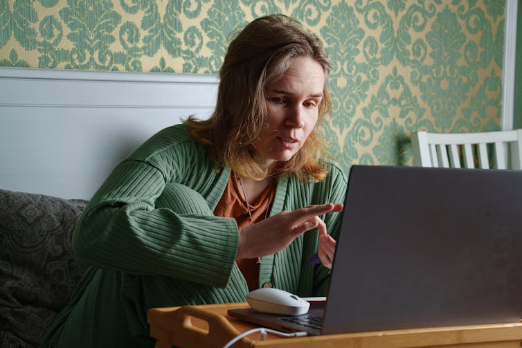 A woman works on her laptop in bed.