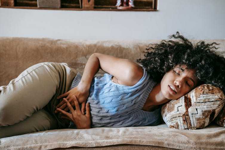 The colored woman clutches her stomach in pain.