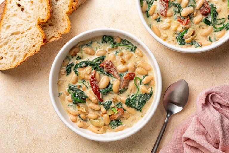 A bowl of stew with bread nearby.