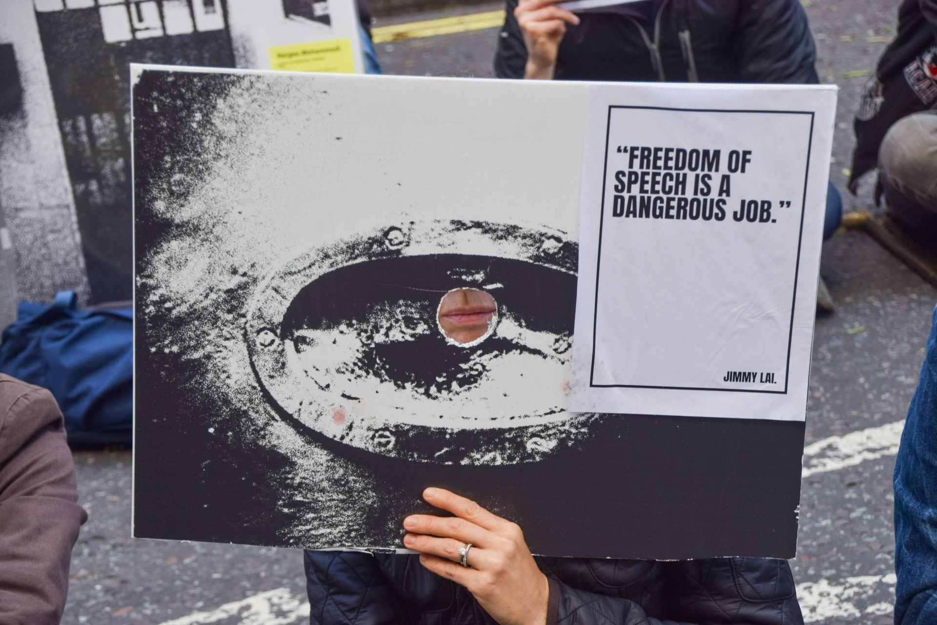 A protester holds a sign with a quote from Jimmy Lai on free speech in front of their face at a demonstration in London, November 2024.