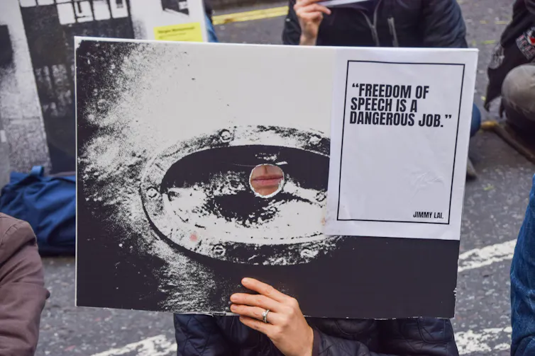 A protester holds a sign with a quote from Jimmy Lai on free speech in front of their face at a demonstration in London, November 2024.
