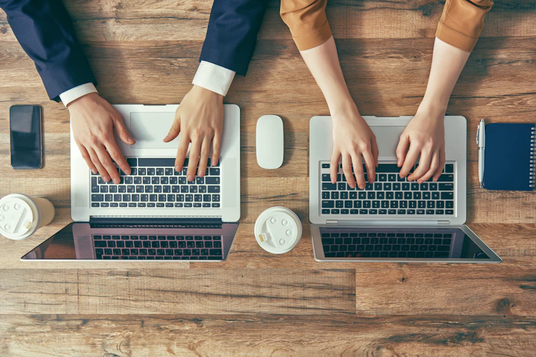 aerial shot of man and woman with their hands on their laptops