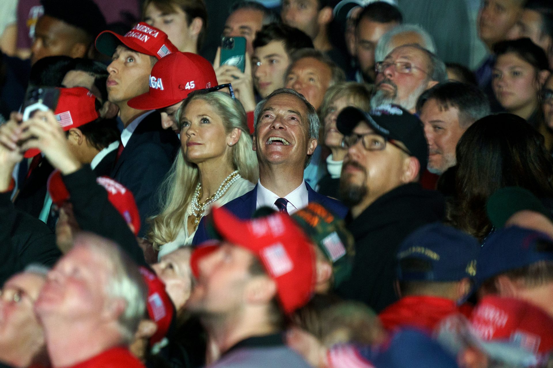 Nigel Farage in a crowd of people wearing read Maga hats.