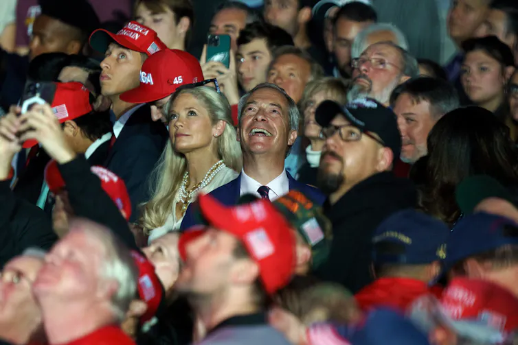 Nigel Farage in a crowd of people wearing read Maga hats.