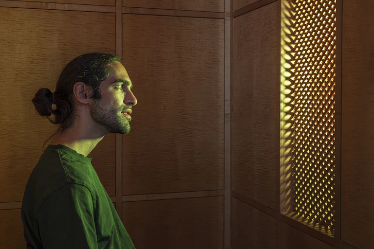 A hologram of an AI Jesus behind a latticework screen.
