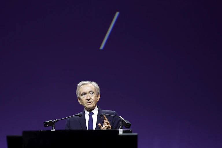 Bernard Arnault devant un pupitre sur un fond violet