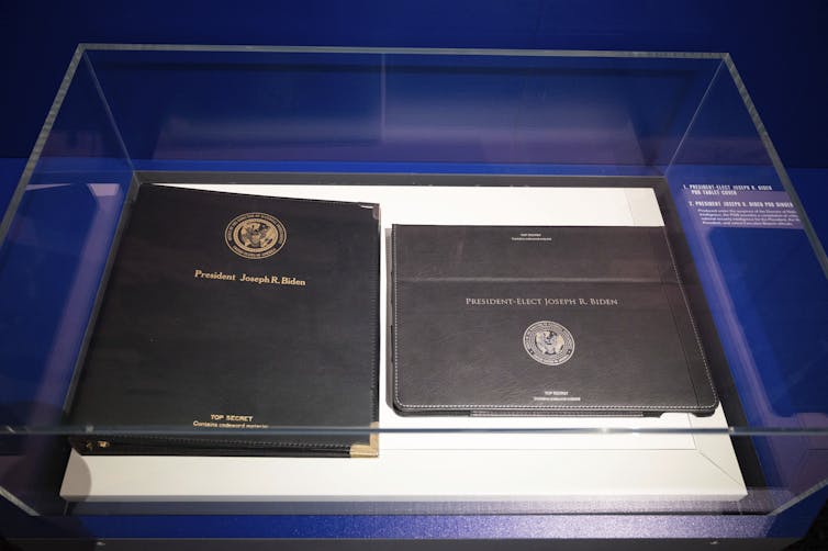 Two brown notebook covers that have 'President Joseph R. Biden' and 'TOP SECRET' printed on the front.