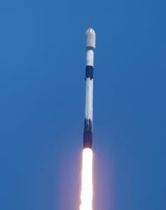 Against a blue sky, a rocket shoots off into space.