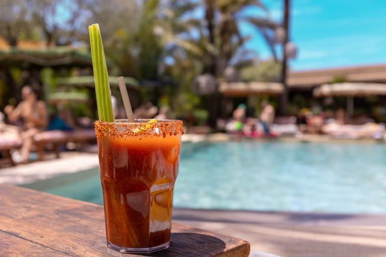 Bloody Mary cocktail on table at edge of outside swimming pool