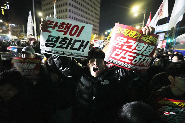 A man in a protest holds up two signs in Korean