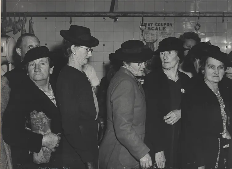 A row of women lining up to buy meat at the butcher's shop.